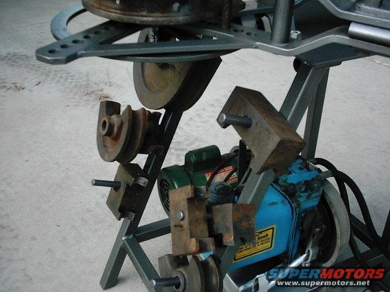 Machinery with pulleys, motor, and metal brackets on a stand