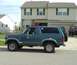 1982 Ford Bronco - A side view of a dark blue Ford Bronco is parked on a residential street in front of a house.