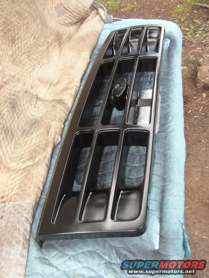 black grille with rectangular openings and a central circular emblem, laid on a quilted blanket