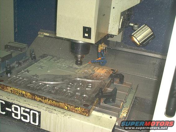 CNC machine engraving a metal plate with text and stars. Machine model C-950 visible