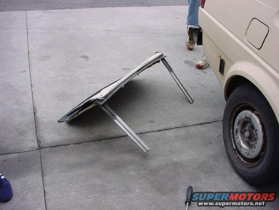 folded metal frame on pavement next to a car wheel