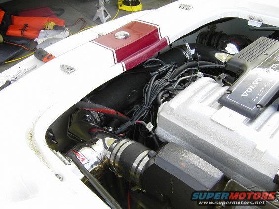 Boat engine bay with Volvo Penta engine, intake pipes, and wiring. Life vests are visible in the background