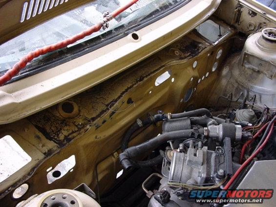 Car engine bay with hoses and wiring visible