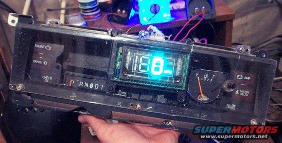 Car dashboard gauge cluster with digital speedometer and analog fuel gauge