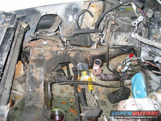 car's engine bay, engine removed, showing frame and components