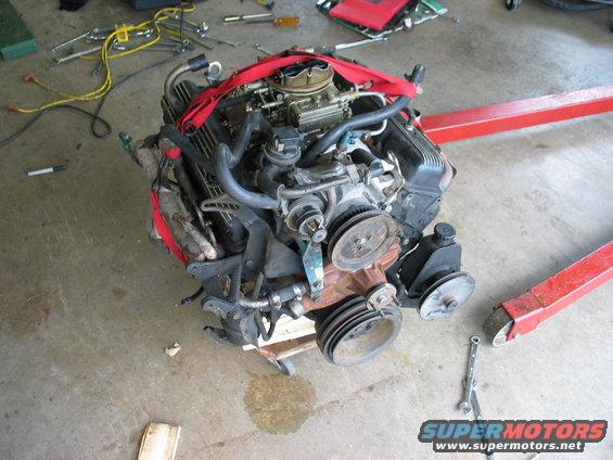 Engine on stand with red straps, tools scattered around