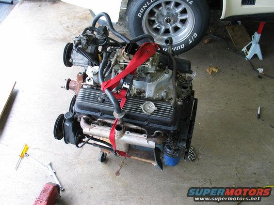 V8 engine with red straps, on an engine stand. Tools on the floor