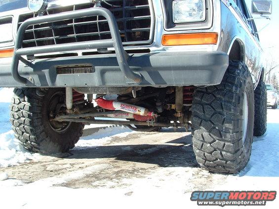 Front view of a lifted 1979 Ford Bronco with large tires and a brush guard. Red shocks are visible