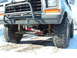 1979 Ford Bronco - This modified 1979 Ford Bronco features oversized tires and a prominent brush guard, with visible red shocks on the suspension.