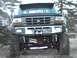 1979 Ford Bronco - This black Ford F-series truck features a prominent 4x4 badge on the front bumper and appears to be lifted with large off-road tires.