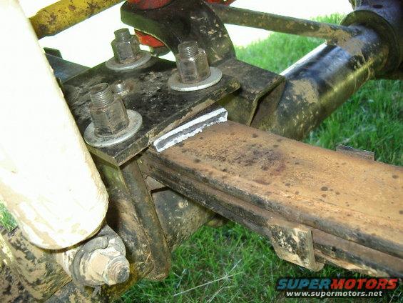 Close-up of rusty leaf spring with U-bolts and mounting bracket