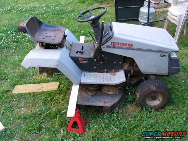 Gray Craftsman lawn tractor with red jack and wooden blocks
