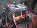 1981 Ford Bronco - A close-up view of a vehicle battery, identified as an EverStart model, secured with a metal bracket and connected by thick red and black c…