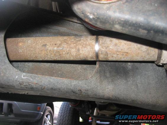 Undercarriage view showing a rusty exhaust pipe and part of another vehicle below