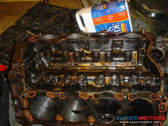 Engine block with orange gasket material, covered in oil and grime