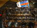 1986 Ford Mustang - Engine block with orange gasket material, covered in oil and grime, with a bottle of cleaning fluid in the background.