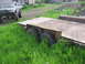 1989 Ford Bronco - A modified pickup truck sits beside a trailer, both partially obscured by overgrown grass.