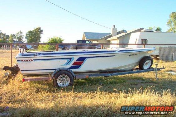White boat with blue and red stripes on a trailer