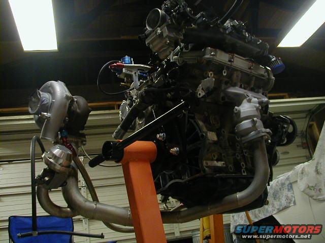 Engine on an orange stand with a turbocharger and exhaust manifold
