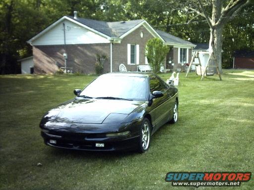 Black 1995 Ford Probe parked on a grassy lawn in front of a house