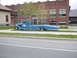 1979 Ford Bronco - A vintage blue tow truck with a long flatbed trailer is parked on the grass beside a brick building.
