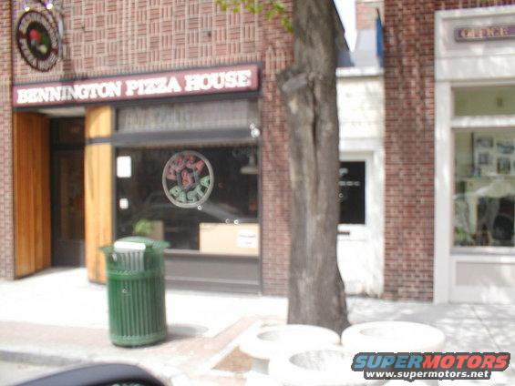 Bennington Pizza House storefront with a green trash can and a tree in front