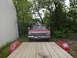 1979 Ford Bronco - A red 1979 Ford Bronco is parked in front of a building, viewed from the bed of a trailer.