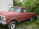 1979 Ford Bronco - This 1979 Ford F-150 pickup truck is seen from the side, parked in a grassy area near a building.