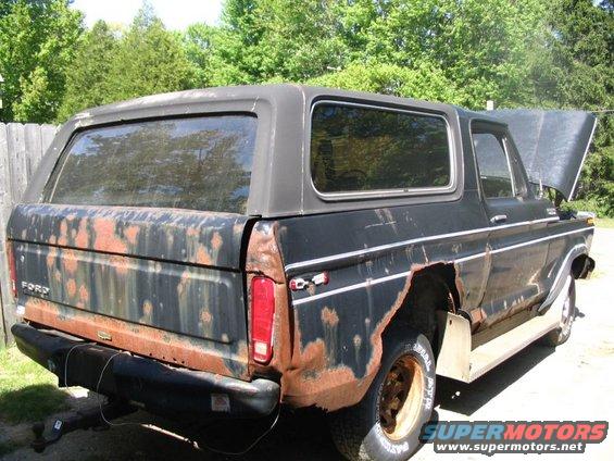 Rear view of a rusty black 1978 Ford Bronco with a soft top