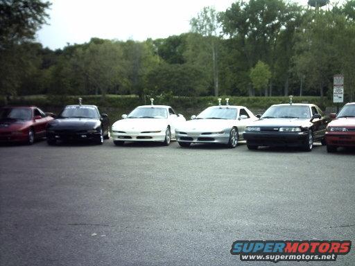 six cars parked in a lot, including a red one, black one, two white ones, and a black one