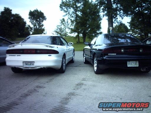 Two 1995 Ford Probe cars, one white and one black, parked on pavement