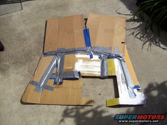 Cardboard cutout taped together, looks like a rough shape of a car part