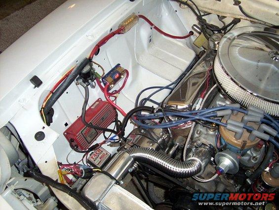 White engine bay with red ignition module, chrome air cleaner, and blue spark plug wires