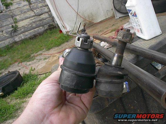Hand holding a new ball joint next to an old one