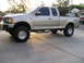 1999 Ford F-150 - Side view of a lifted 1999 Ford F-150 pickup truck with custom wheels and running boards.