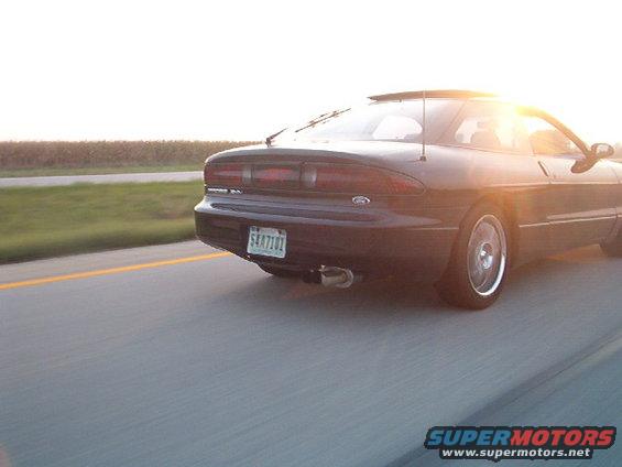 1995 Ford Probe driving on highway at sunset, rear view