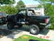 1986 Ford Bronco - Black Ford Bronco with its doors removed, parked next to another vehicle in a driveway.