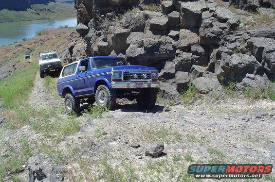 Blue 1978 Ford Bronco on a rocky off-road trail with a river in the background