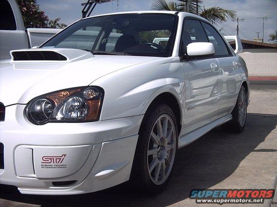 White Subaru WRX STI sedan front 3/4 view with STI badge on bumper