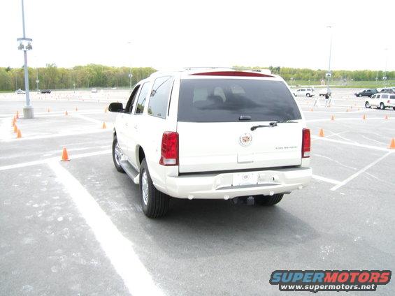 Rear view of white Cadillac Escalade parked in a lot with orange cones