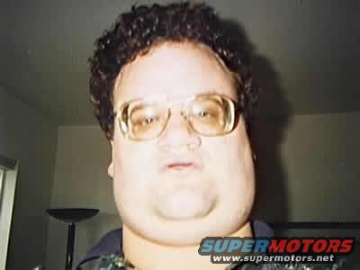 Man wearing large glasses and curly hair, looking at the camera