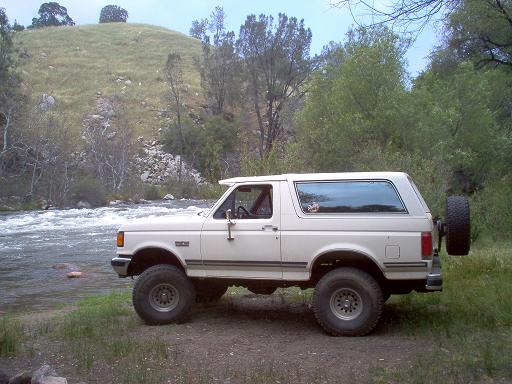 White 1988 Ford Bronco parked by a river, side view