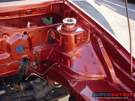 engine bay strut tower with red paint, showing suspension mount and some brake lines
