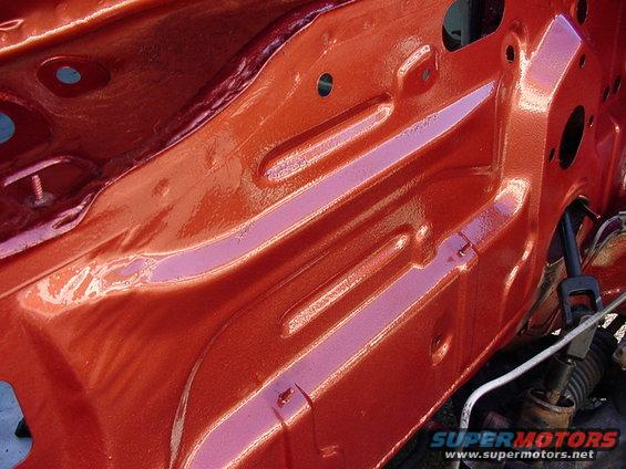 Orange painted engine bay structure with visible metal bracing and wiring