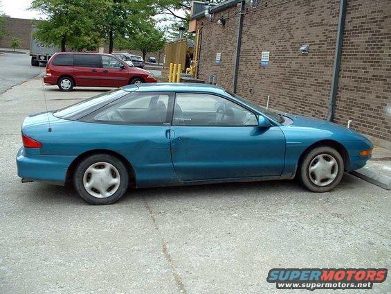 1993 Ford Probe coupe, side view, parked on concrete. Red minivan in background