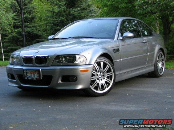 Silver BMW M3 coupe parked on a driveway with trees in the background. License plate reads JR 073