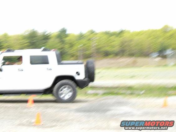 White SUV, possibly a Hummer H2, seen from the side with a spare tire mounted on the rear door