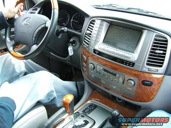 Car interior with wood trim, Lexus steering wheel, and navigation screen displaying a caution message