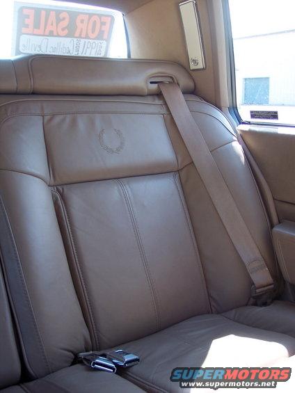 Brown leather car interior with Cadillac crest on headrest and seatbelt