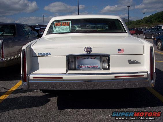 White 1991 Cadillac DeVille rear with 'FOR SALE' sign in window and North Carolina license plate